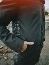 Campera verde oscuro con estampado de dibujos en blanco en el frente. Corte recto, con cierre frontal y bolsillos laterales con cierre.