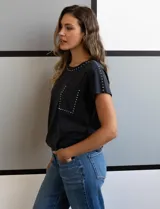 Remera gris de algodón con cuello redondo, mangas cortas y bolsillo en el pecho. Apliques de tachas plateadas en cuello, hombros y bolsillo.