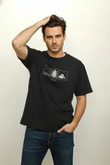 Remera de algodón negra de manga corta y corte holgado, con cuello redondo. Presenta un estampado frontal minimalista en blanco con tres recuadros que contienen ilustraciones de paisajes y arquitectura oriental, incluyendo la palabra "HAZINO".