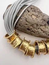 Collar con múltiples cuerdas grises y aros dorados texturizados.