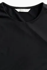 Remera negra de punto elástico, de corte ajustado, con cuello redondo y mangas largas.