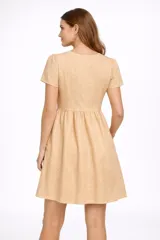 Vestido corto negro de broderie, con mangas cortas abullonadas y escote en V. Presenta un corte imperio con frunce en la cintura y falda acampanada.