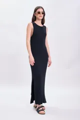 Vestido largo de punto negro con cuello redondo y sin mangas. Tiene corte recto y aberturas laterales en el ruedo.
