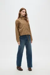 Campera color camel con estampado de lunares negros, cuello alto y cierre frontal. Tiene mangas largas y cordón ajustable en el dobladillo.