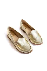 Mocasines dorados de cuero con costuras a la vista.