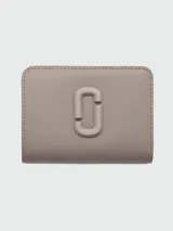 Billetera compacta Marc Jacobs modelo The Covered J Marc Mini, color gris topo, confeccionada en cuero, con logo "J" cubierto en el frente y cierre perimetral con cremallera.