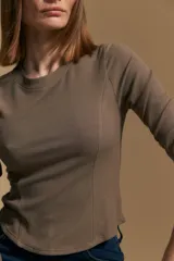 Remera blanca de manga larga con tejido acanalado, cuello redondo y corte ajustado al cuerpo. Presenta costuras verticales que definen la silueta.