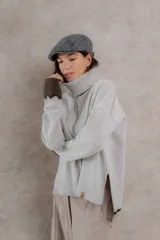 Sweater de punto color gris claro, con cuello alto, mangas largas y corte holgado.