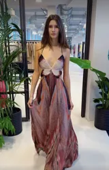 Vestido largo con breteles finos y espalda descubierta. Presenta un top en forma de mariposa bordada con paillettes y una falda vaporosa con transparencias sutiles y estampado en tonos cálidos.