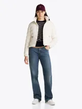 Campera Tommy Hilfiger color blanco, acolchada con plumón, de corte regular. Tiene cuello chimenea, capucha plegable, cierre de cremallera, dos bolsillos laterales con cremallera, puños elásticos con botones a presión y parche con el logo de la marca en la manga.