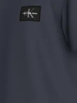 Remera azul de algodón de corte regular, cuello redondo y mangas cortas. Presenta una pequeña insignia con el monograma de Calvin Klein en el pecho.