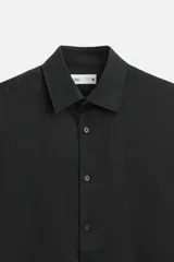 Camisa blanca de corte regular, cuello italiano, manga larga con puños abotonados y cierre frontal con botones.