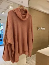 Poncho tejido color salmón con cuello alto volcado.