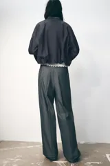 Pantalón ancho gris con textura de espiga, tiro alto, doble cintura elástica ajustable con cordón, pinzas frontales, bolsillos delanteros y falso bolsillo de vivo en la espalda.