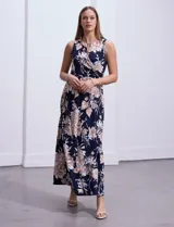 Vestido maxi de seda fría con estampado floral en tonos beige y azul marino, de la marca Sandra Darren. Tiene cuello alto entrelazado con abertura ojal y aplique metálico.