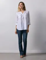 Blusa blanca de lino y rayón, con cuello a la base, escote en V y abertura con botones. Tiene bolsillos en la parte delantera y mangas largas regulables con presilla y botón.