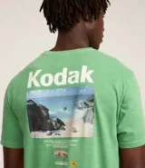 Remera verde con estampa de la marca Kodak y photoprint de playa paradisíaca.