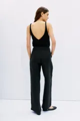 Pantalón palazzo negro de tiro alto, confeccionado en cupro y viscosa. Cuenta con bolsillos diagonales laterales, bolsillos ojal falsos en la espalda y cierre lateral invisible.