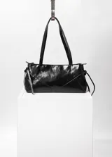 Cartera negra de cuero con forma alargada, cierre metálico color níquel y bolsillo interno con cierre. Interior 100% algodón.