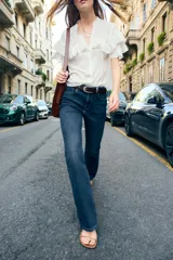 Pantalón de jean azul oscuro, de tiro bajo, corte slim fit y bootcut. Con cinco bolsillos y cierre frontal con cremallera y botón.