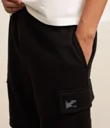 Bermuda masculina color marrón oscuro, confeccionada en tela French Terry, con cintura elástica y cordón de ajuste. Presenta bolsillos cargo funcionales a los lados.