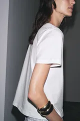 Camiseta blanca de cuello redondo y manga corta con estampado de texto en azul.