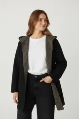 Saco largo de tejido de punto color camel, con capucha y bolsillos frontales. El interior de la capucha y el borde frontal tienen un estampado geométrico en tonos beige y marrón.