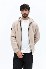 Campera con cierre de algodón color beige claro, con capucha ajustable mediante cordones y logo bordado en el pecho. Presenta bolsillos laterales y puños y ruedo acanalados.
