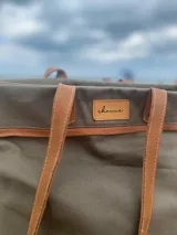 Bolso de lona color negro con detalles en cuero marrón, con bolsillo interno y forro de tela.