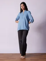 Blusa celeste en lyocell, con cuello a la base con solapa, escote en V y abertura central con botones. Manga larga regulable con presilla y botón.
