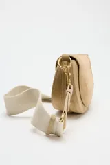 Bandolera de gamuza color beige, con asa corta y cierre imantado.