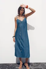 Vestido midi de denim azul, con escote en pico y tirantes finos.