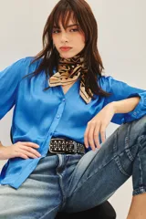 Camisa celeste de poliéster con cuello mao y mangas largas con frunces en hombros, espalda y puños. Cierre frontal con botones a tono.
