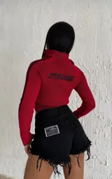 Short de jean negro con cintura alta, cierre frontal con botón y cremallera, bolsillos delanteros y traseros, y ruedo desflecado.