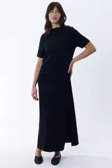 Vestido largo negro de corte recto con cuello redondo y mangas cortas. Presenta aberturas laterales en el ruedo.