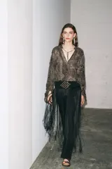 Camisa de viscosa con estampado paisley en blanco y negro. Cuello redondo con escote pico ajustable con cordones, mangas largas con elástico y volantes en los puños, bajo asimétrico y cierre frontal con botones forrados.