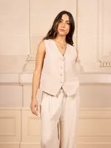 Chaleco negro de lino con corte sastrero, escote en V y cierre frontal con botones plateados.