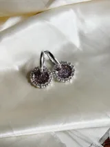 Par de aros colgantes con argolla de acero quirúrgico, dije circular de resina negra y borde de strass plateado.