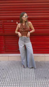 Pantalón de jean celeste de tiro medio con pierna extra ancha y caída fluida, con bolsillos delanteros y traseros, y cierre frontal con cremallera y botón metálico.