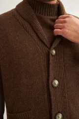 Cardigan tejido color marrón con cuello smoking, cierre con botones y bolsillos delanteros.