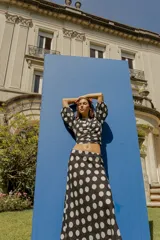 Blusa corta negra con estampado de lunares blancos, escote redondo, mangas abullonadas 3/4 y frunce central.