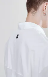 Camisa manga larga blanca de calce oversize confeccionada en textil fresco y liviano, con bolsillo ojal en delantero y cartera escondida.