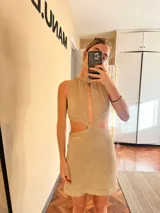 Minivestido dorado de tejido de punto con lurex, cuello halter con abertura central, cut-outs laterales y espalda descubierta.