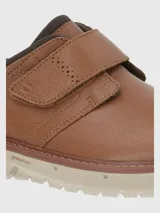 Zapato de cuero color marrón claro con ajuste de velcro y suela de goma color crema.