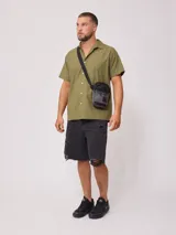 Bandolera negra de poliéster con correa ajustable y logo estampado.