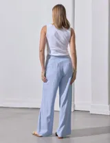 Pantalón celeste a rayas verticales, de lino, corte wide leg y tiro alto con botones decorativos.