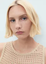 Top tejido al crochet color beige, con cuello redondo, tirantes anchos y detalle de flores bordadas en el frente.