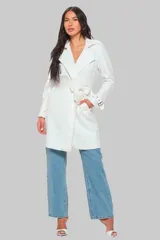 Trench largo color blanco de cuero vegano, con cuello solapa, cierre cruzado con lazo y bolsillos laterales.