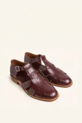 Sandalia marrón de cuero vacuno con diseño de tiras entrecruzadas, hebilla lateral y taco bajo de 2,5 cm.