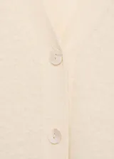 Cardigan color crema de tejido suave con efecto pelo. Tiene escote de pico, cierre frontal con botones y mangas largas.